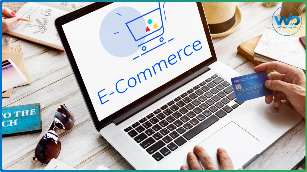 Devant un ordinateur portable affichant « E-Commerce », une carte bancaire est tenue prête, illustrant la simplicité et la sécurité des transactions en ligne | wdata-mg.info